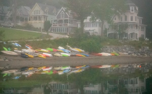 colorful kayaks and Victorian cottages reflected in bay on a foggy morning