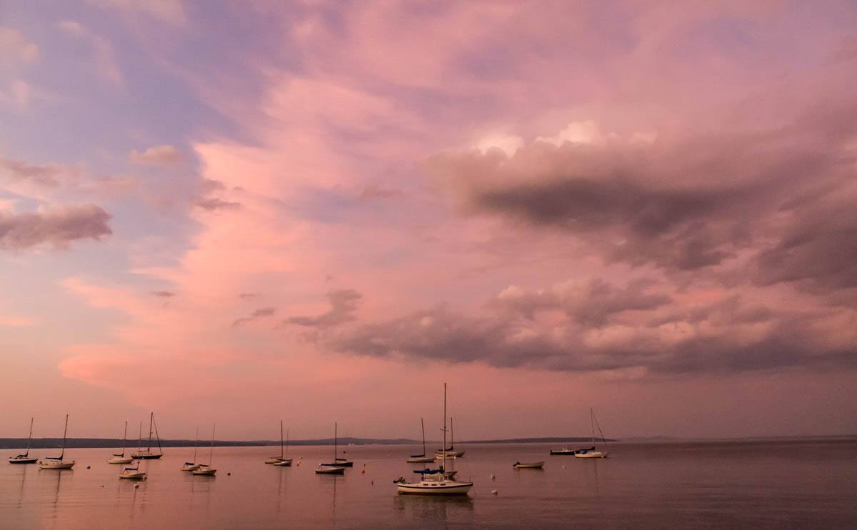 twilight clouds tinged pink above sailboats in Bayside harbor