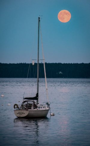 full moon rising over Islesboro with sailboat at anchor below