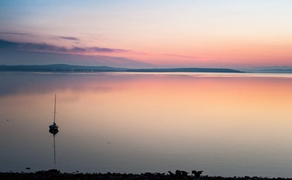 solitary sailboat at anchor on calm water before sunrise, Bayside Harbor