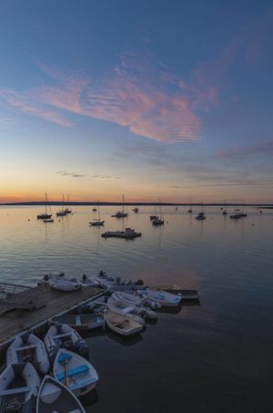 A cluster of dinghies at the Bayside dock, under a colorful dawn sky