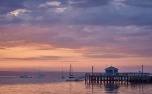 waterfront scene under cloudy dawn sky