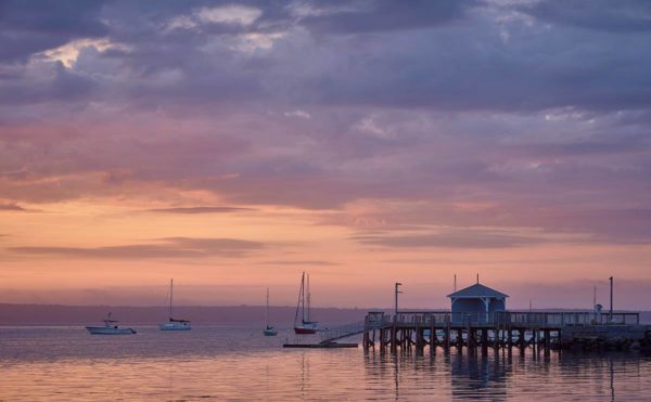 waterfront scene under cloudy dawn sky